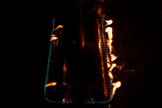 Orange flame along a row of gas burners in the dark.